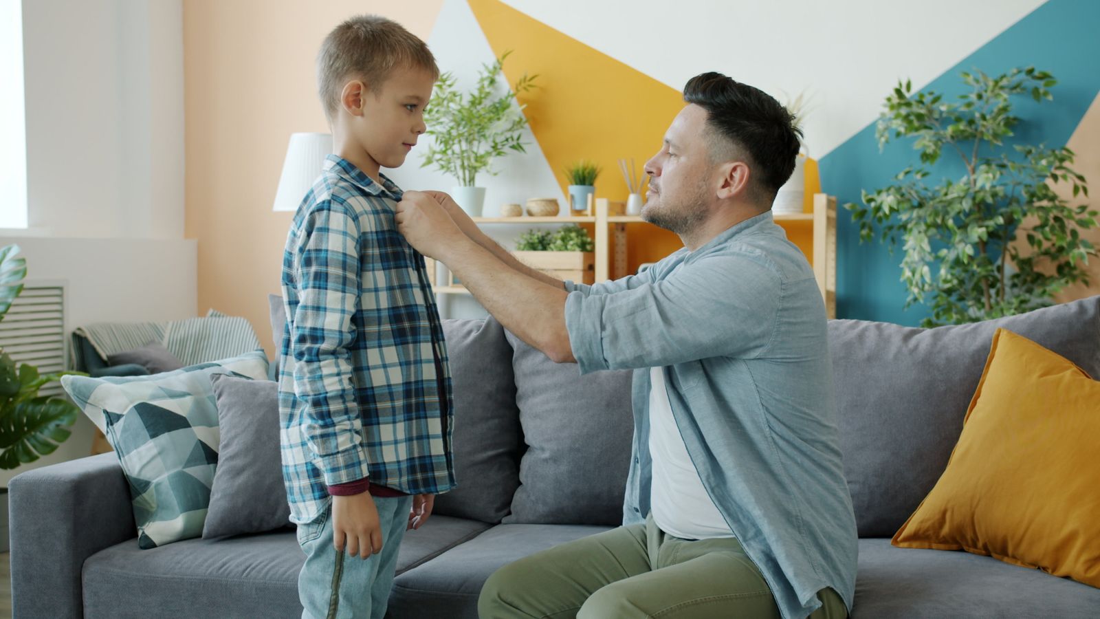 A parent helping a child get dressed in the living room